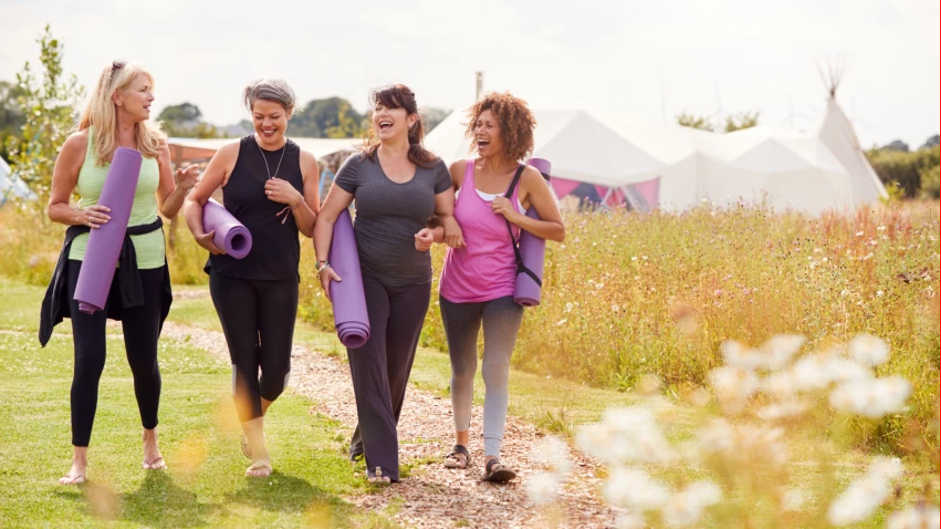 Four women with yoga mats heading to a yoga class.